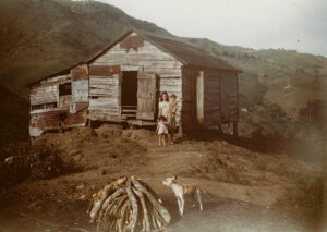 Woman with two children in front of house, dog and f(family?) [1948 c.a.] Fundación Luis Muñoz Marín > Colección Menonitas > Clayton Gingerich 10,11605. 