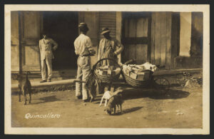 Quincallero (1900–1915.ca)(Vendedor con cestas, coladas estas en una carretilla, vende su mercancía a un parroquiano) Waldrop Photographic Co. Col. Atilio Moscioni Chesi [1897-1917] Biblioteca Digital Puertorriqueña 